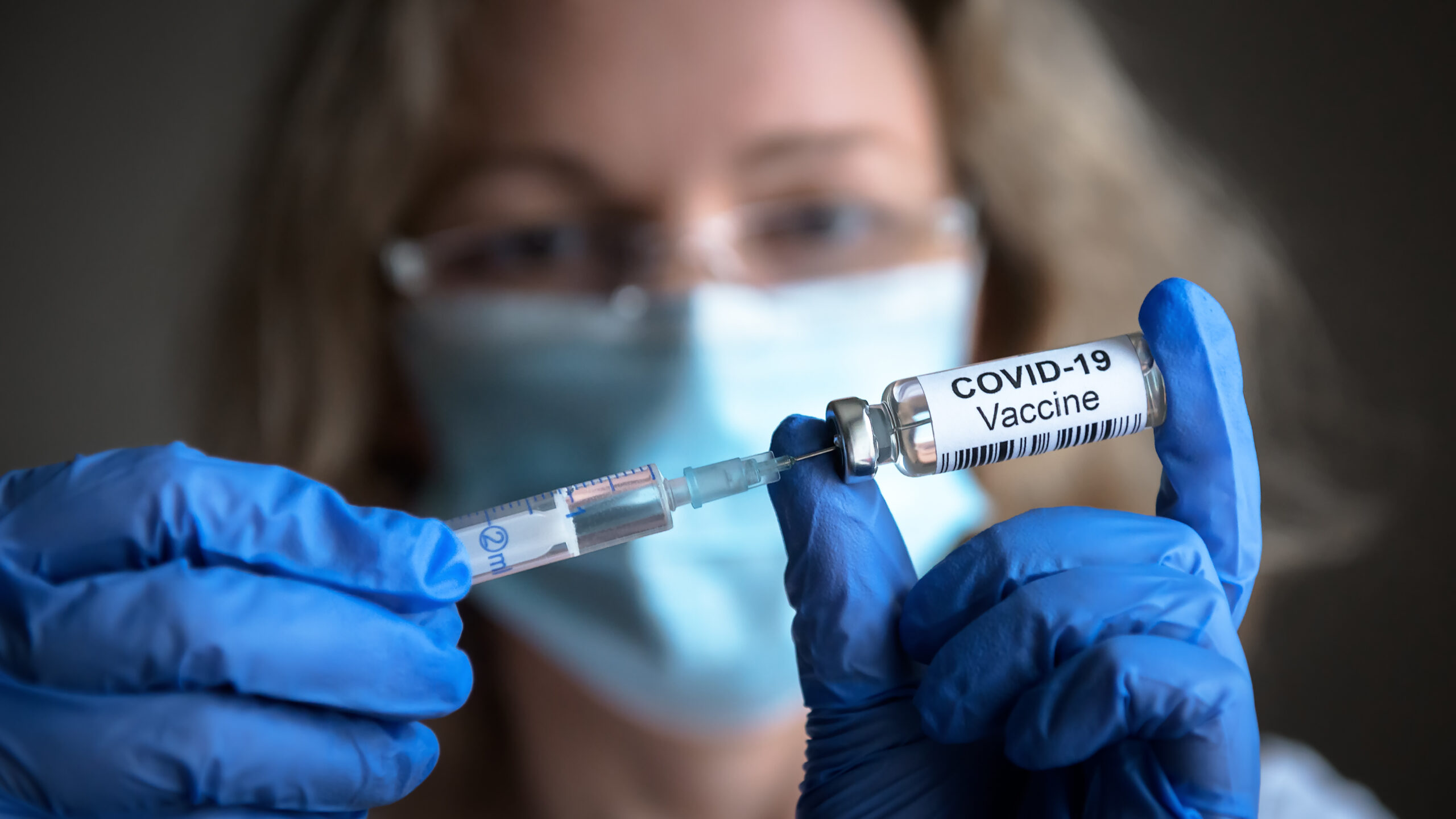 A health professional drawing a COVID-19 vaccine into a syringe
